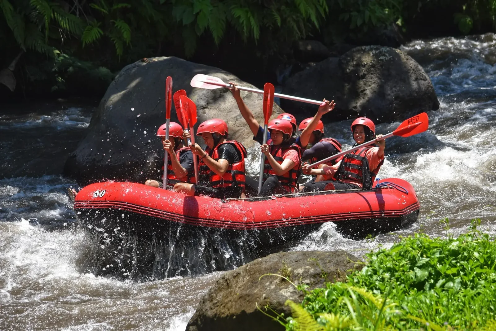 Guests and a rafting guide in a red raft on the Ayung River in Bali