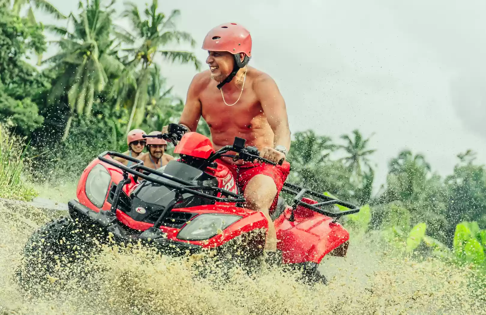 Single rider on a red Dadi ATV splashing through a wet off-road track near Ubud
