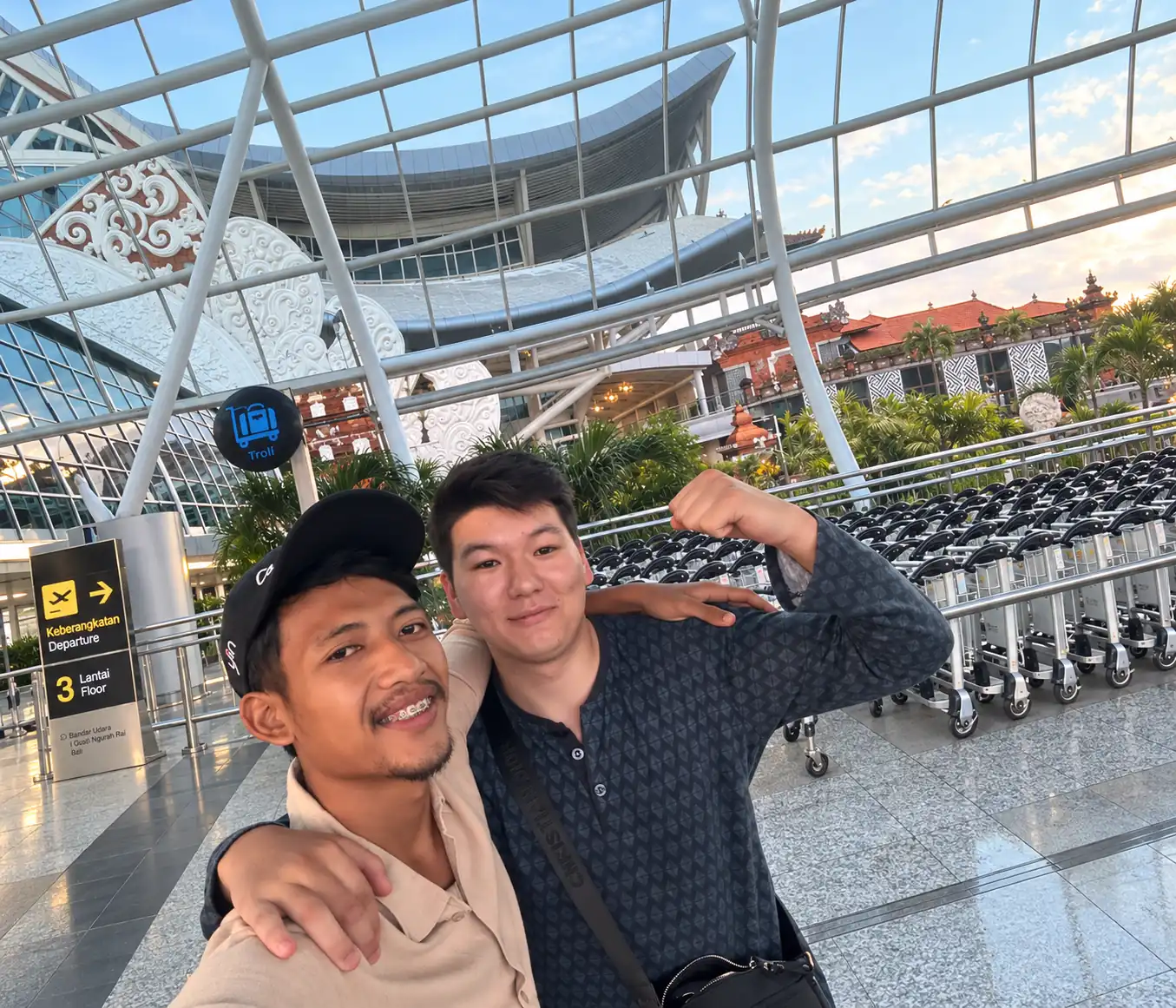 Selfie at Ngurah Rai Airport with the terminal and luggage trolleys in the background