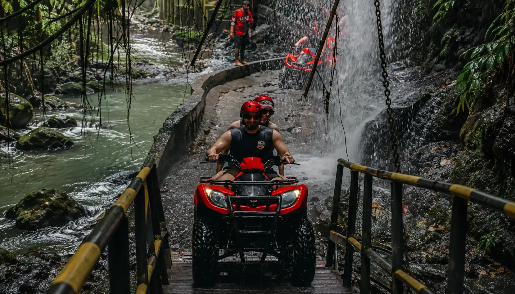 Jambe Asri ATV riders crossing the waterfall bridge on the Barong Cave route near Ubud